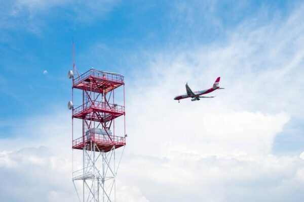 Airplane flying next to a red iron tower